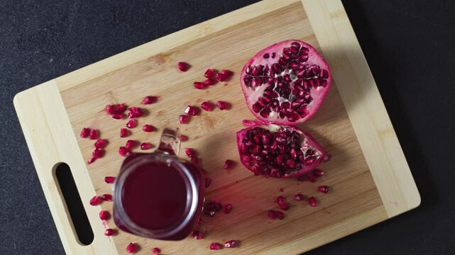 Cutted pomegranate with seeds lie on a wooden cutting board on the concrete background