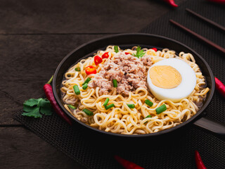 Instant noodle soup with minced pork and half boiled egg in pan on wooden table background. Asia Food