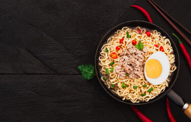 Top view of instant noodle soup with minced pork and half boiled egg in pan on wooden table background. Asia Food