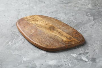 One wooden serving board on light grey textured table, closeup. Space for text