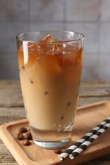 Tasty iced coffee and beans on wooden table, closeup