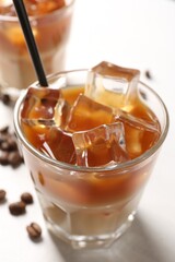 Tasty iced coffee and beans on white table, closeup