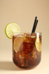 Tasty Cuba Libre cocktail in glass on beige background