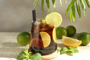 Tasty Cuba Libre cocktail in glass and ingredients on light textured table, closeup