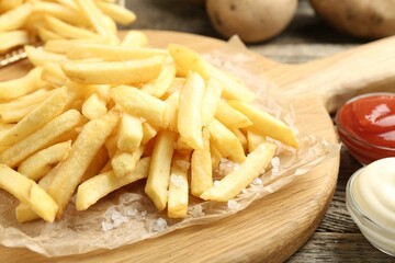 Tasty french fries served with sauces on wooden table, closeup