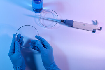 Scientist with Petri dish on light background, closeup
