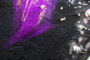 Textured black wall with vibrant purple graffiti, distressed concrete surface. Urban grunge, 90s,...