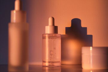 Two serums and a cream in a jar in the rays of the sun.