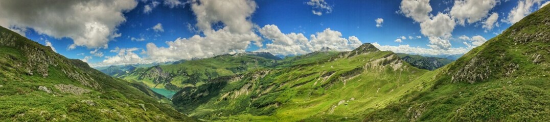 Naklejka premium Panoramic view of scenic green valleys and lush mountain peaks under blue skies