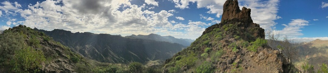Panoramic view of rugged cliffs and green valleys under a cloudy sky