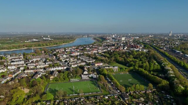 Smooth forward drone flight over suburban gardens, football fields, and Cologne cityscape