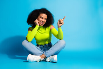 Young woman in neon green attire showcases positive energy with a cheerful gesture, sitting...