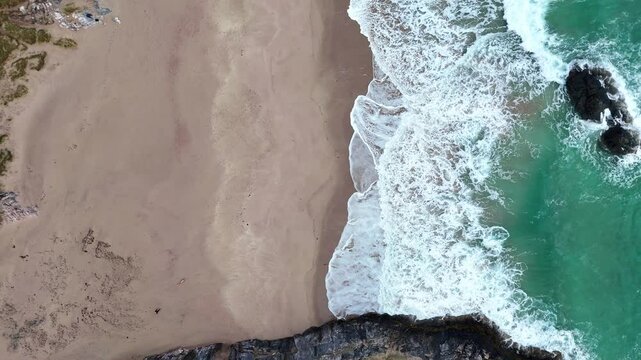 Drone ascending on the beach of Sango sands viewpoint with foamy waves in Scotland