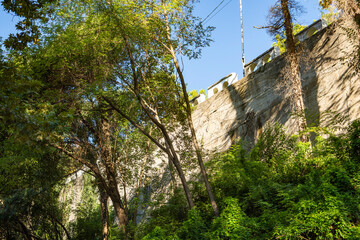 A beautiful scenic mountain road surrounded by lush greenery and under a bright blue sky. View of the road from below