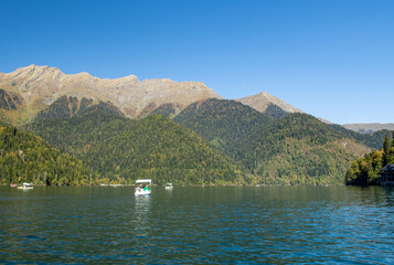 Lake Ritsa is nestled in the embrace of the mountains. Boats glide along its calm, azure surface....
