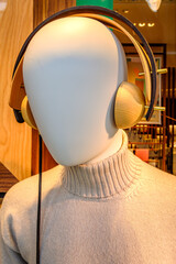 Stylish mannequin displaying unique wooden headphones and a cozy sweater in a modern retail store during the daylight hours