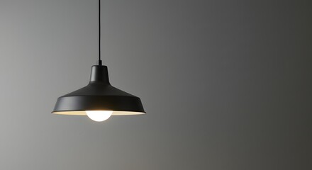 A black pendant light hangs against a gray wall illuminating the space below it