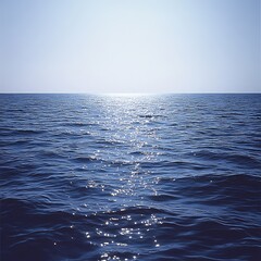 Fototapeta premium Calm blue ocean with gentle ripples reflecting sunlight, creating a peaceful and serene seascape under a clear, bright sky.