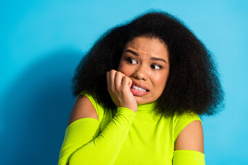 Charming young woman with curly hair in neon green casual outfit expressing a thoughtful emotion...