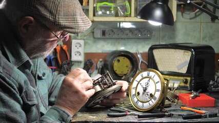 Vintage clockwork. The hands of an old master carefully adjust an antique clockwork, bringing it back to life. Restoration of antiques.
