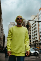 Young Black man walking in the city wearing neon clothes and sunglasses