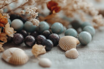 Natural seashells and gemstone beads placed on a soft surface with dried flowers evoke beach-inspired jewelry making and coastal craft aesthetics.

