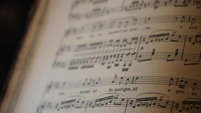 Slow camera slide reveals the harmonious language of aged music sheets, with faded symbols and warm light highlighting the elegant flow of romantic melodies, textures stand out