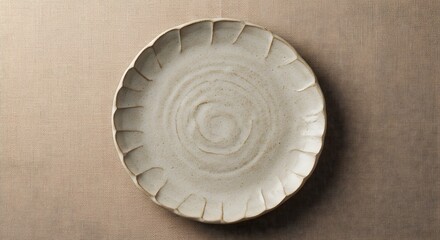 A simple ceramic plate with a scalloped edge on a textured neutral background surface
