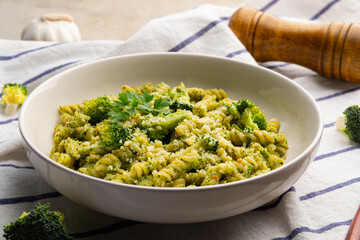 Vegetarian vegan green pasta, small spiral pasta with broccoli pesto sauce and vegan cheese in...