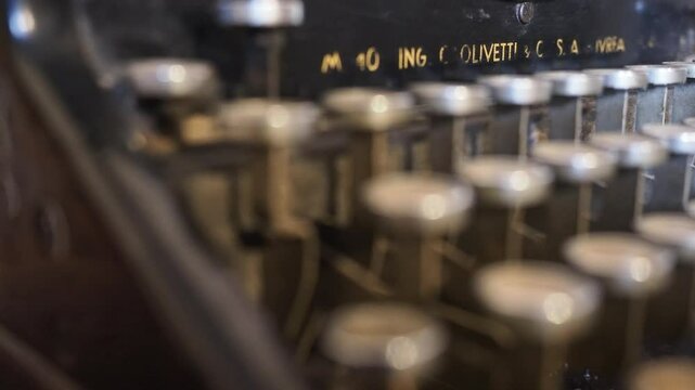 Camera slides gently across worn Olivetti M40 typewriter, capturing patina on metal keys, textured casing and nostalgic traces of past words once crafted, evoking vintage mechanical beauty