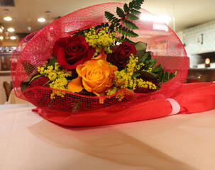 bouquet of flowers with red roses and an orange rose resting on the table after the wedding party