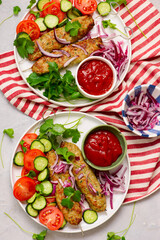 Chicken Lula Kebab with fresh vegetables and hot sauce on a platter.top veiw