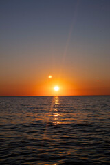 Fototapeta premium The sun is setting over the ocean, casting a warm glow on the water