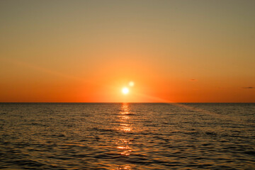 The sun is setting over the ocean, casting a warm glow on the water