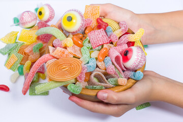 Colorful candies in the hands of a child on a white background