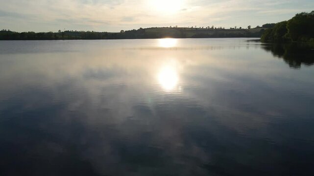 Low drone shot of sunset sun reflection on picturesque lake. Emy Lough, Monaghan, Ireland