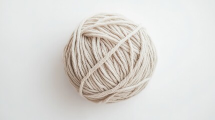 Soft beige yarn ball against white surface, perfect for knitting and crochet projects, craft themes, or creative designs