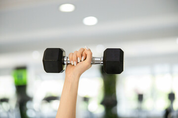 Female hand gripping dumbbell in overhead press position, isolated focus on strength and form.