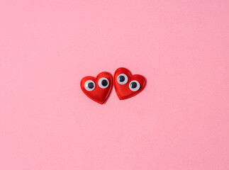 Two cute decorative hearts with googly eyes on pink background.Empty space for text or design