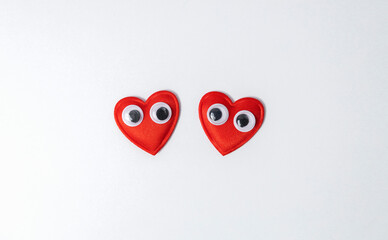 Two decorative hearts look at each other, white background. Concept of lovely couple