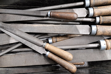 Old metal files collection. Vintage metalworking rasps with wooden handles. Industrial hand tools used in workshop. Close-up of textured surfaces and aged craftsmanship. Toolset for shaping and filing