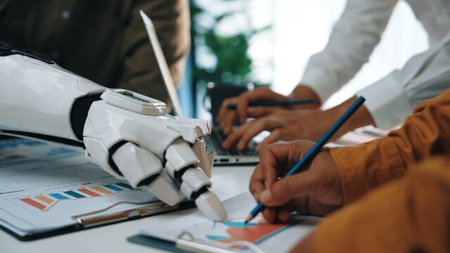 A modern workspace scene showcasing a robotic hand assisting in brainstorming activity. The image highlights technology's role in enhancing collaboration and innovation.Noogenesis