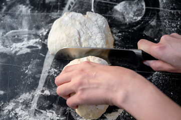 Cutting dough into pieces with a kitchen knife. Traditional Ukrainian varenyky with cottage cheese...