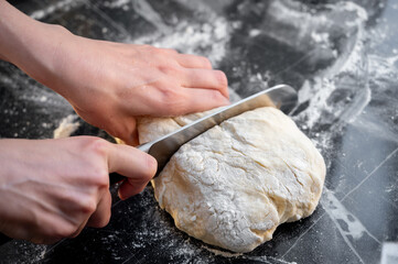 Cutting dough into pieces with a kitchen knife. Traditional Ukrainian varenyky with cottage cheese...