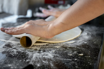 Rolling out the dough with a rolling pin. Traditional Ukrainian varenyky with cottage cheese — step-by-step process of home cooking. Hands at work, fresh ingredients and real Eastern European cuisine.