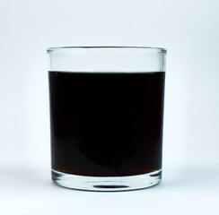 Dark drink served in a clear glass cup on white background