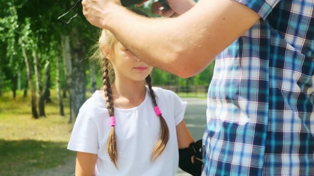 Father helped her daughter wear a yellow helmet while enjoying time together in the park
