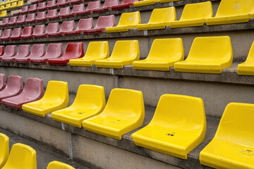Plastic yellow and red seats in a sports stadium with no people