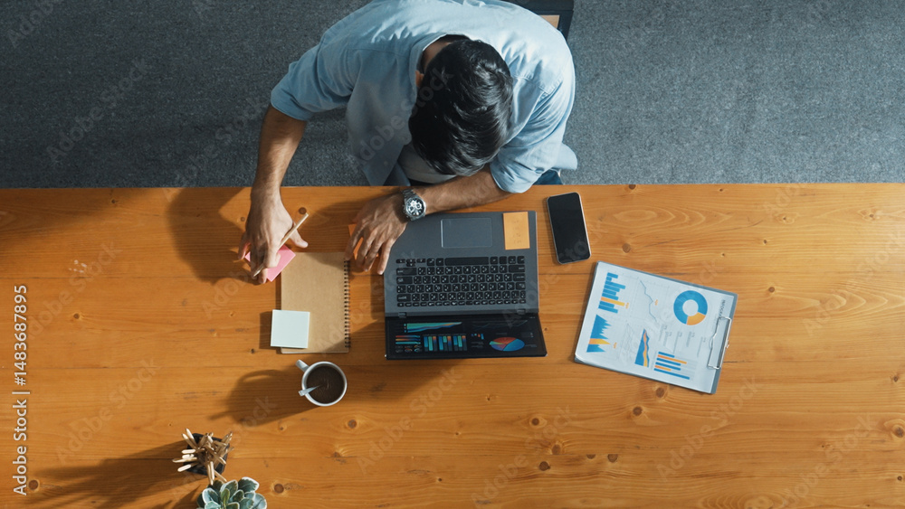 Poster skilled businessman writing idea on colorful sticky notes while looking at data analysis. caucasian 