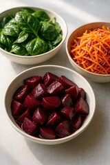 Spinach salad, roasted beetroot chunks, and shredded carrot-cabbage salad in ceramic bowls under natural light

